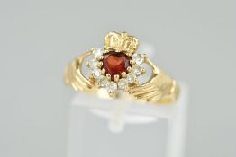 A GEM SET CLADDAGH RING designed as a heart shape garnet within a colourless paste surround, ring