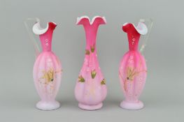 A PAIR OF PINK SATIN GLASS EWERS, together with matching vase, all florally decorated, approximate