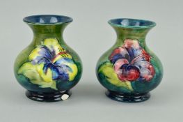 A PAIR OF SMALL MOORCROFT POTTERY VASES, 'Hibiscus' pattern on green ground, paper labels to base,