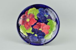 A MOORCROFT POTTERY PLATE, 'Clematis' pattern on dark blue ground, impressed marks to base,