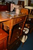 A WALNUT FRAMED SINGER SEWING MACHINE, an oak two door cabinet, an oak circular table, two chairs,