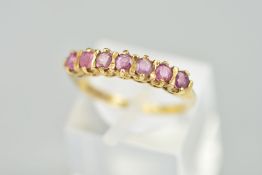 A 9CT GOLD SEVEN STONE RUBY RING, designed as a line of claw set circular shape rubies with bar