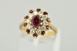 A 9CT GOLD GARNET CLUSTER RING, designed as a central oval garnet within a cubic zirconia surround