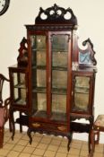 AN EDWARDIAN CARVED MAHOGANY GLAZED FOUR DOOR VITRINE, the middle section revealing three shelves