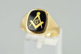 A 9CT GOLD SIGNET RING, designed as a black panel engraved with gold Masonic symbolism and the
