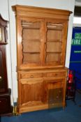 A VICTORIAN PITCH PINE BOOKCASE, the double glazed doors revealing three adjustable shelves, above