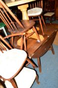 A DARK ERCOL ELM DROP LEAF DINING TABLE together with five stick back chairs including one carver (