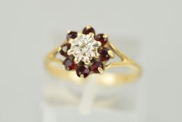 A 9CT GOLD GARNET AND DIAMOND CLUSTER RING designed as a central illusion set, single cut diamond