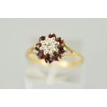 A 9CT GOLD GARNET AND DIAMOND CLUSTER RING designed as a central illusion set, single cut diamond