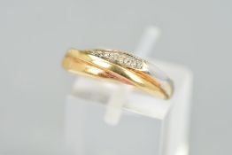 A 9CT GOLD DIAMOND DRESS RING, of bi-colour overlapping design partly set with three single cut
