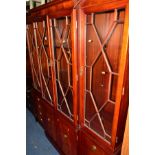 A REPRODUCTION MAHOGANY BREAKFRONT GLAZED FOUR DOOR BOOKCASE above a cupboard base flanked by