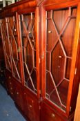 A REPRODUCTION MAHOGANY BREAKFRONT GLAZED FOUR DOOR BOOKCASE above a cupboard base flanked by