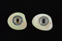 TWO EARLY 20TH CENTURY GLASS EYES, one a light greyish colour, the other a grey/blue, one with a
