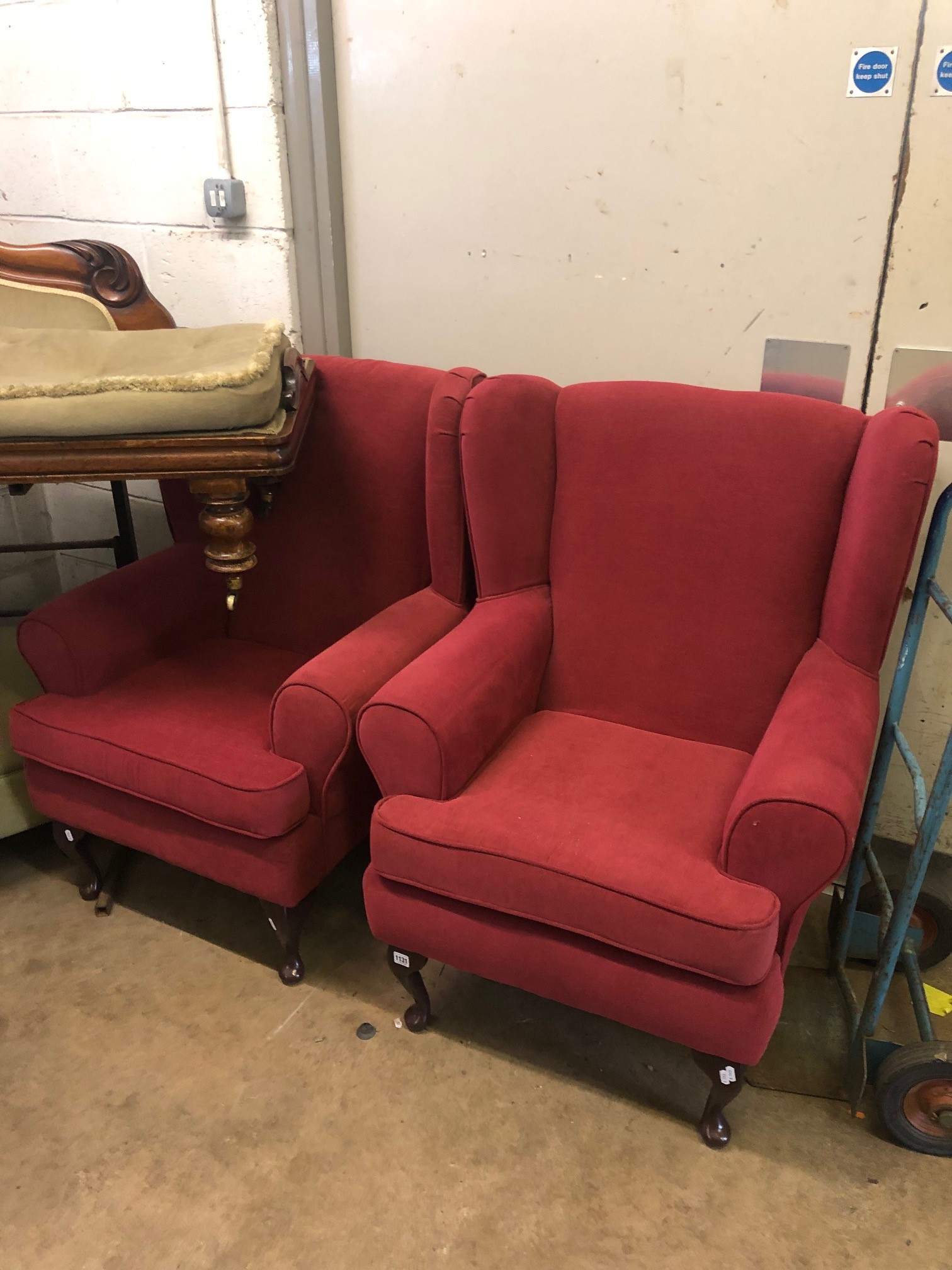 A PAIR OF RED UPHOLSTERED WING BACK ARMCHAIRS