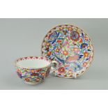 A MEISSEN CUP AND SAUCER having polychrome clobbered decoration, blue crossed swords backstamp,