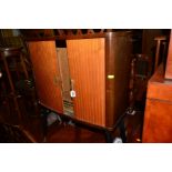 A 1950'S MAHOGANY ROLL FRONT CABINET on four tapering legs (appears to a case from a vintage bush