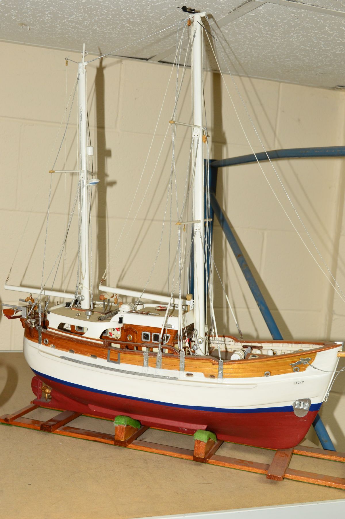 A WOODEN SCRATCH BUILT MODEL OF A FISHING VESSEL painted red and white on a wooden stand,