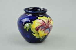 A SMALL MOORCROFT POTTERY VASE, 'Hibiscus' pattern on blue ground, paper label to base, height 7cm