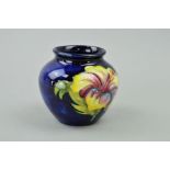 A SMALL MOORCROFT POTTERY VASE, 'Hibiscus' pattern on blue ground, paper label to base, height 7cm