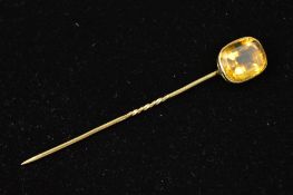 A CITRINE STICKPIN, designed as a rectangular citrine within a collet setting, length 80mm, weight