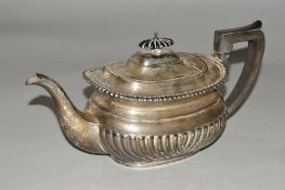 AN EDWARDIAN SILVER TEAPOT OF GEORGIAN STYLE, gadrooned rim, half reeded, ebonised fitments,