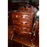 A REPRODUCTION CARVED MAHOGANY BEDSIDE CHEST OF THREE DRAWERS