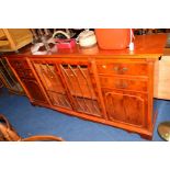 A MODERN YEW WOOD GLAZED BOOKCASE/SIDEBOARD with four drawers, approximate width 194cm