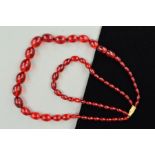 A DOUBLE ROW OF RED PLASTIC BEAD NECKLACE, designed as graduated oval shape beads measuring 11mm