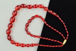 A DOUBLE ROW OF RED PLASTIC BEAD NECKLACE, designed as graduated oval shape beads measuring 11mm