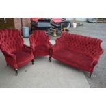 AN EDWARDIAN MAHOGANY THREE PIECE PARLOUR SUITE, covered in red buttoned velour upholstery,