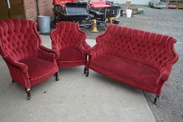 AN EDWARDIAN MAHOGANY THREE PIECE PARLOUR SUITE, covered in red buttoned velour upholstery,
