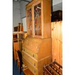 AN OAK LEAD GLAZED BUREAU/BOOKCASE, together with a low oak chest of three drawers and an oak