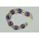 A GEM BRACELET, designed as an oval amethyst cabochons within scrolling rope twist surrounds flanked