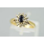 A 9CT GOLD SAPPHIRE AND DIAMOND CLUSTER RING, designed as a central oval sapphire within a single