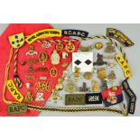 A RED CANVAS BANK CASH BAG, containing a large number of badges, patches, shoulder devices, buttons,