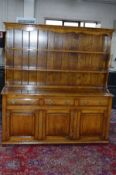 A REPRODUCTION TUDOR OAK DRESSER, the top section with a two tier plate rack above three drawers and