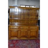 A REPRODUCTION TUDOR OAK DRESSER, the top section with a two tier plate rack above three drawers and