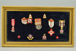 A GLAZED FRAME CONTAINING A COLLECTION OF BRITISH RED CROSS MEDALS, lapel badges and achievement