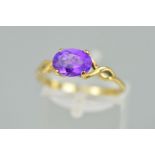 A 9CT GOLD AMETHYST RING, designed as an oval amethyst within a four claw setting to the open