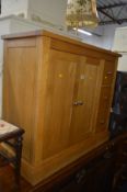 A LIGHT OAK SIDEBOARD flanked by three deep drawers and double cupboard doors, width 97cm x depth