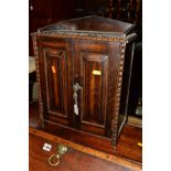 AN EARLY 20TH CENTURY OAK TWO DOOR SMOKERS CABINET revealing two drawers and a seperate ash tray