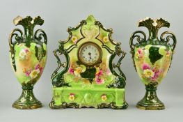 A CERAMIC CLOCK GARNITURE, florally decorated on green ground with gilt overlay, one hand loose on