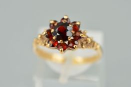 A 9CT GOLD GARNET CLUSTER RING, the central circular garnet within a tiered circular garnet surround