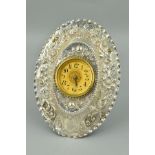 A LATE VICTORIAN EASLE BACKED SILVER MOUNTED OVAL CLOCK, repousse decorated with foliate scrolls and