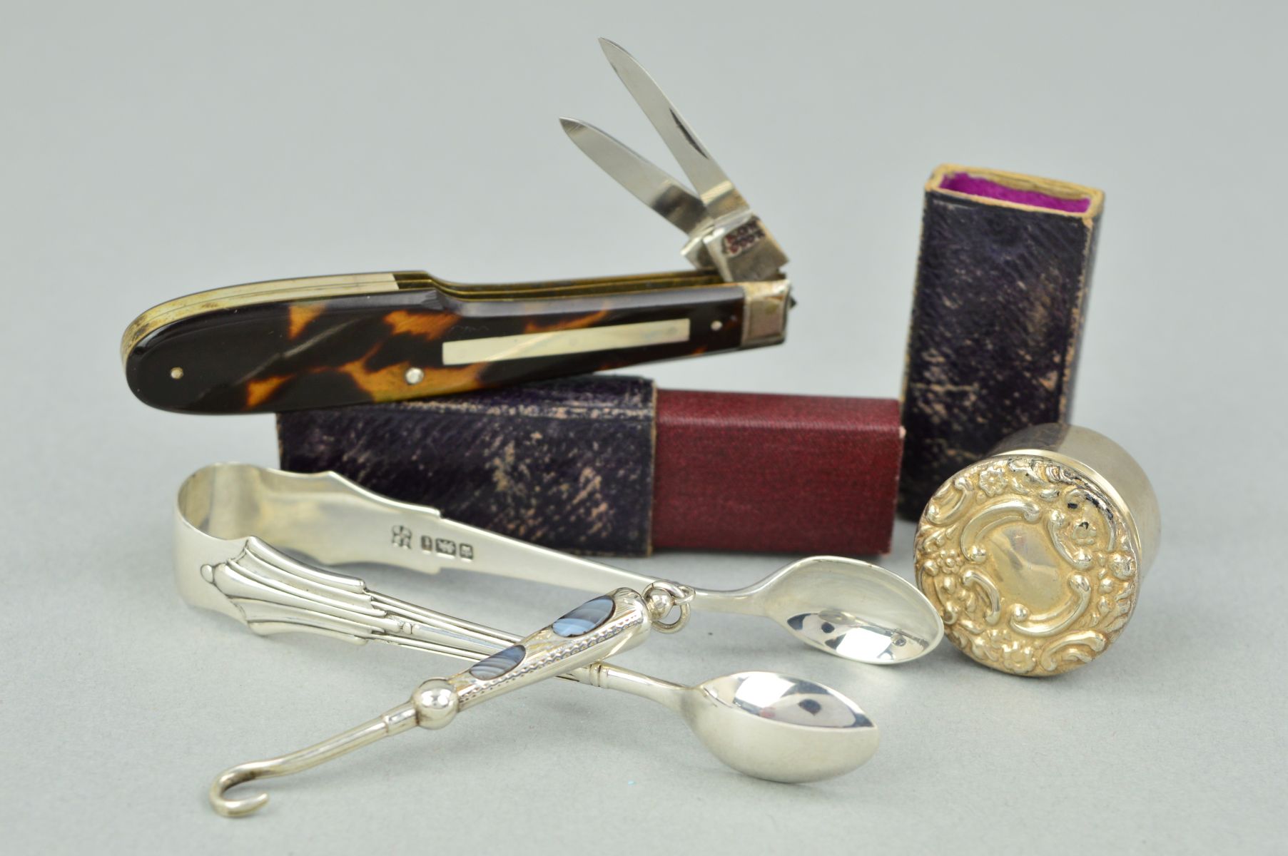 FOUR ACCESSORIES to include a pair of silver sugar tongs, a silver circular pill box with embossed