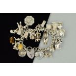 A SILVER CHARM BRACELET, the curb link charm bracelet suspending 26 charms to include a hinged