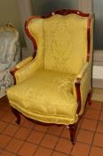 A REPRODUCTION FRENCH WINGED ARMCHAIR with yellow floral upholstery