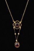 AN EARLY 20TH CENTURY GOLD GEM PENDANT designed as an oval garnet within an open flower shape