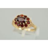 A 9CT GOLD GARNET CLUSTER RING, the central oval garnet within a garnet surround, with leaf detail