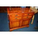 A REPRODUCTION MAHOGANY DROP LEAF SIDE TABLE with three various drawers above double cupboard doors